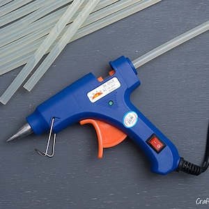 May include: A blue and orange hot glue gun with a black cord and a clear glue stick. The glue gun has a power switch and a temperature control dial. The glue stick is 20W.