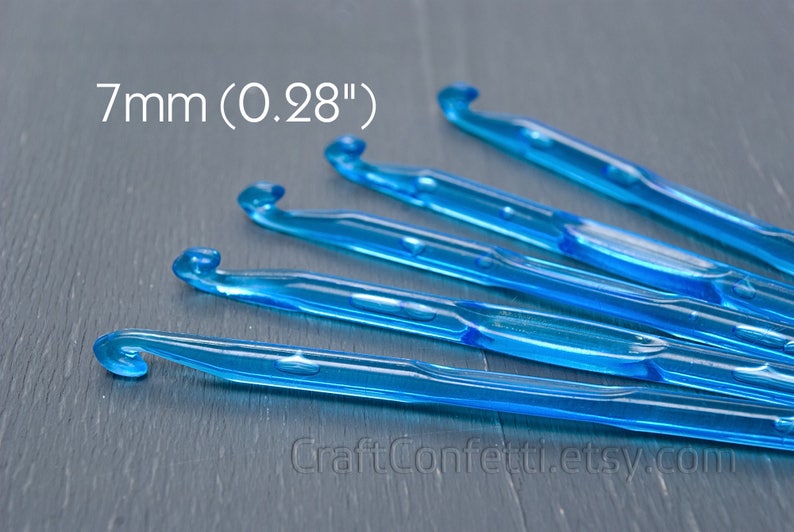 May include: A set of six blue plastic crochet hooks, each measuring 7mm (0.28 inches) in size. The hooks are arranged in a fan shape on a gray surface.