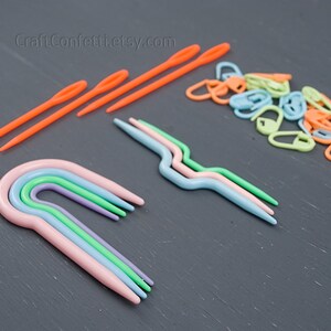 Puede incluir: Un conjunto de agujas de crochet de pl&aacute;stico de colores vivos y marcadores de punto. Las agujas son de varios tama&ntilde;os y colores, incluyendo rosa, verde, azul y morado. Los marcadores de punto son de varios colores, incluyendo naranja, verde, azul y amarillo. CraftConfetti.etsy.com