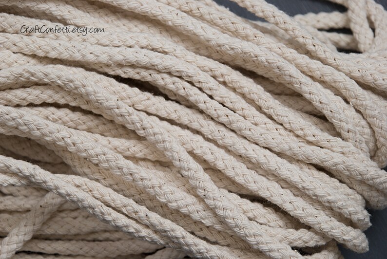 May include: Close-up of a pile of natural white cotton rope. The rope is braided and has a soft, textured surface.