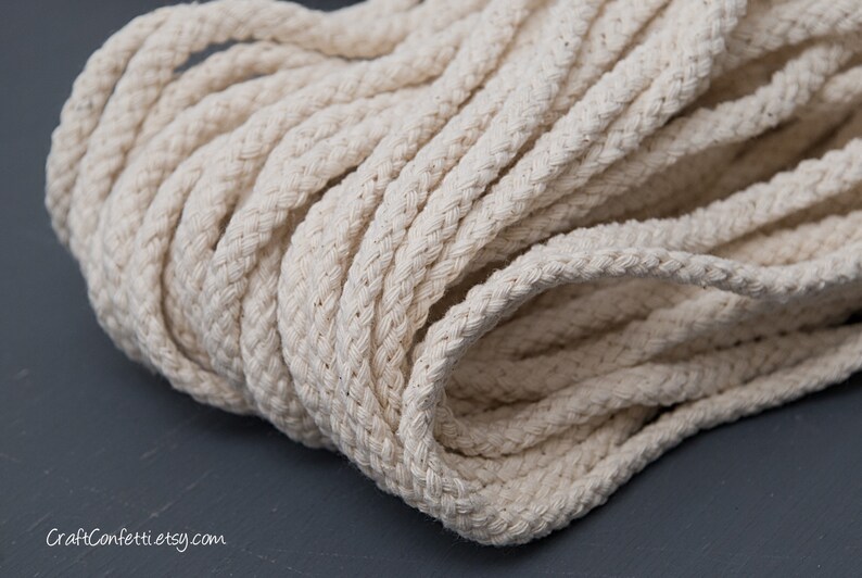 May include: Close-up of a thick, natural-coloured cotton rope. The rope is tightly wound and has a soft, textured surface.