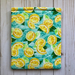 May include: A teal blue fabric pouch with a lemon and lime print. The pouch has a white background with yellow lemons and green limes.