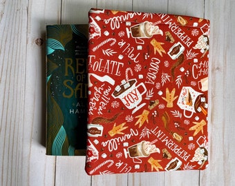 May include: A red book cover with a winter holiday theme. The cover features a repeating pattern of hot chocolate, marshmallows, peppermint sticks, and gingerbread men. The text "Hot Chocolate" and "Peppermint" are visible on the cover.