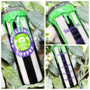 Puede incluir: Un vaso de acero inoxidable con un dise&ntilde;o de rayas blancas y negras, rematado con detalles verdes goteando. El vaso presenta un logotipo circular con el texto "BEETLEJUICE COFFEE" y una ilustraci&oacute;n de personaje. El lateral del vaso dice "Sandworm Juice".
