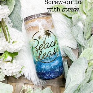 May include: A stainless steel tumbler with a screw-on lid and straw. The tumbler features a beach-themed design with gold lettering that says "Beach please". The design includes shades of blue, white, and gold glitter.