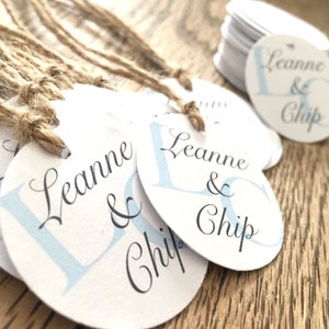 May include: White round gift tags with blue and black lettering. The tags read "Leanne & Chip". The tags are tied with twine.