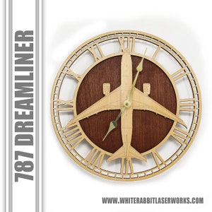 May include: A wooden clock with a 787 Dreamliner airplane design. The clock face is made of wood and has Roman numeral markings. The airplane is cut out of the wood and is in the center of the clock face. The clock hands are gold.