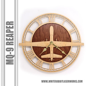 May include: A wooden wall clock featuring an MQ-9 Reaper drone design. The clock has a light wood frame with Roman numerals and a dark wood center. The clock hands are gold-colored. The text "MQ-9 REAPER" is on the left side.