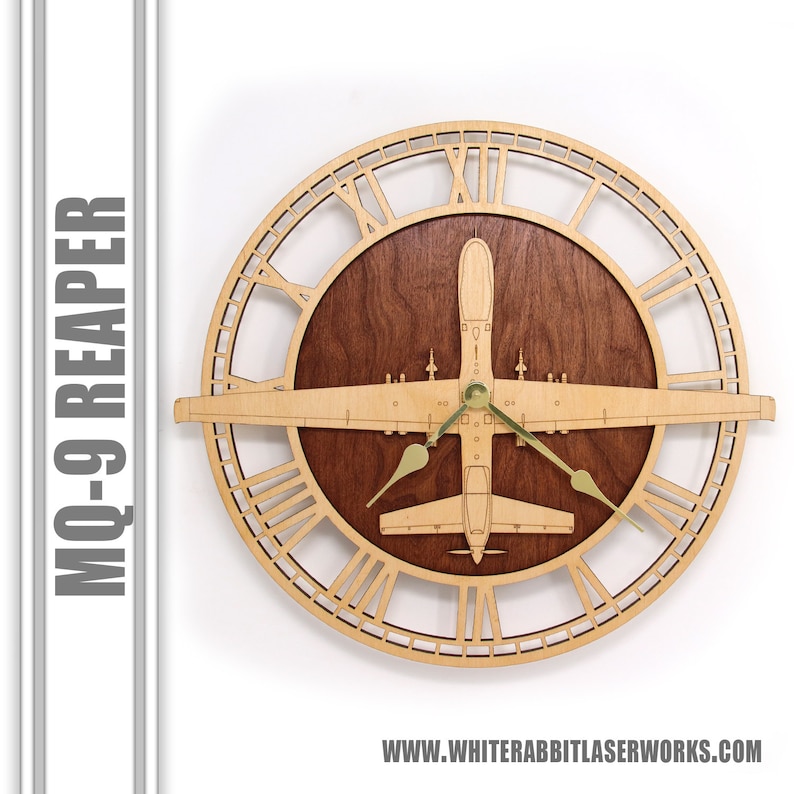 K&ouml;nnte beinhalten: Eine Wanduhr aus Holz mit einem MQ-9 Reaper Drohnen-Design. Die Uhr hat einen hellen Holzrahmen mit r&ouml;mischen Ziffern und eine dunkle Holzmitte. Die Zeiger der Uhr sind goldfarben. Der Text "MQ-9 REAPER" befindet sich auf der linken Seite.
