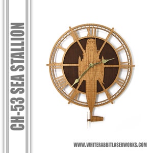 May include: A wooden clock featuring a CH-53 Sea Stallion helicopter design. The clock face is surrounded by Roman numerals and the helicopter is intricately detailed. The clock hands are gold.