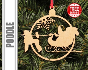 May include: A wooden Christmas ornament featuring a poodle pulling Santa Claus in a sleigh. The ornament is round and has a snowflake design in the center. The ornament is made of light brown wood and has a red ribbon attached to the top.