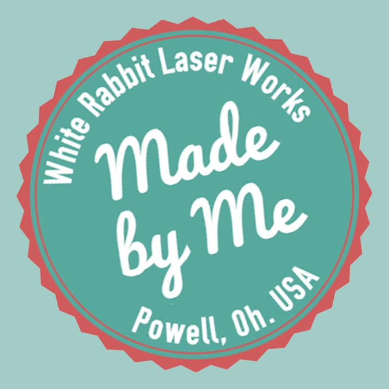 K&ouml;nnte beinhalten: Rundes Logo in T&uuml;rkis und Rot mit dem Text "White Rabbit Laser Works" am Rand. Die Worte "Made by Me" sind in Schreibschrift, mit "Powell, Oh. USA" unten.