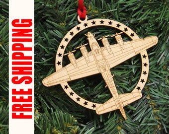 Könnte beinhalten: Ein hölzerner Weihnachtsbaumschmuck in Form eines B-17-Bomberflugzeugs mit einem sternförmigen Kreis darum. Der Schmuck hängt an einem roten Band an einem grünen künstlichen Weihnachtsbaum.