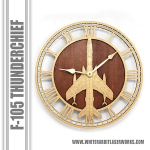 May include: A wooden wall clock with Roman numeral markings and a cutout design of an F-105 Thunderchief jet aircraft. The clock face is brown wood with gold-colored hands.