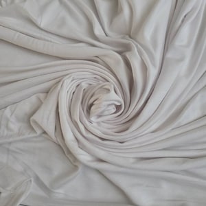 Puede incluir: Tela blanca drapeada y retorcida en forma de espiral.