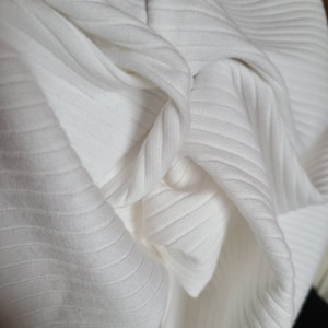 May include: Close-up of white ribbed fabric, showing the texture and folds of the material.
