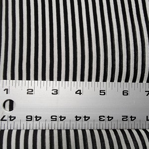 以下が含まれることがあります： 黒と白のストライプの生地と、17.8cm を測定する定規。定規はセンチメートルとミリメートルで目盛りが付けられています。