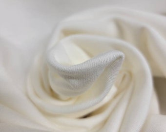 May include: Close-up of a white fabric with a soft, smooth texture. The fabric is folded and draped, creating a smooth, flowing look.