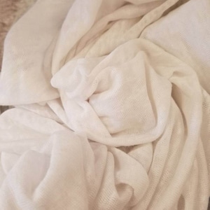 Puede incluir: Tela blanca con una superficie suave y texturizada. La tela est&aacute; drapeada y doblada, creando un aspecto suave y fluido.