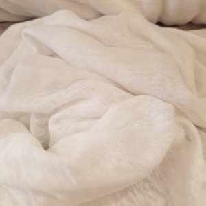 Puede incluir: Tela de lino blanca con una superficie suave y texturizada. La tela est&aacute; doblada y drapeada, creando un aspecto suave y fluido.