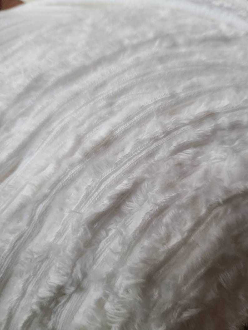 May include: White fluffy yarn with a textured, slightly bumpy surface.