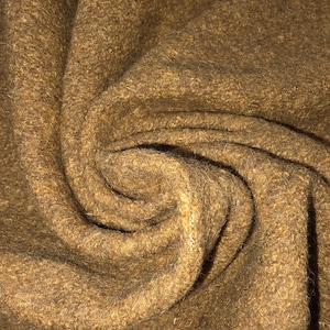 May include: Close-up of a textured, brown fabric with a swirling pattern. The material appears to be thick and possibly wool or a similar textile. The color is a warm, earthy tone.