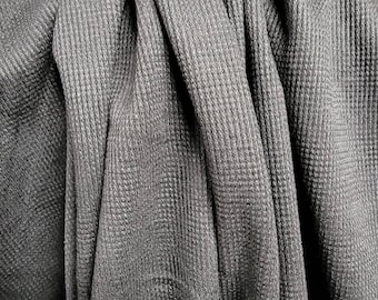 May include: Black waffle knit fabric with a textured surface. The fabric is folded and draped, showing the soft, drapey texture.