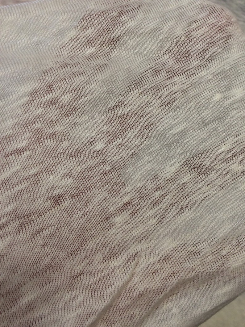 Op de afbeelding: Close-up van een witte gebreide stof met een subtiel textuurpatroon.