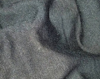 Peut inclure: Gros plan sur un tissu gris foncé avec un tissage texturé. Le tissu est plié, créant des ombres et mettant en valeur la texture. Le matériau semble doux et pourrait être utilisé pour des vêtements ou des textiles de maison.