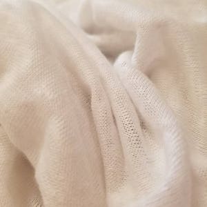 Puede incluir: Primer plano de una tela blanca de punto con una superficie suave y texturizada.
