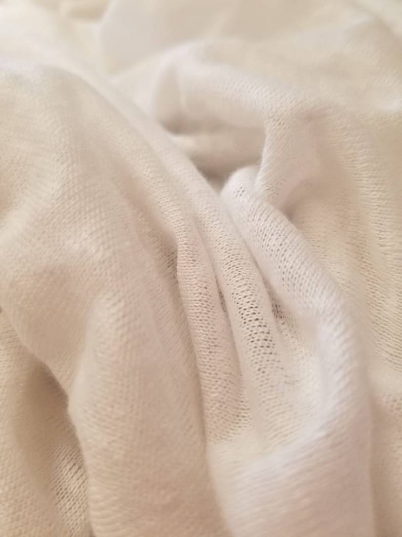 Puede incluir: Primer plano de una tela blanca de punto con una superficie suave y texturizada.