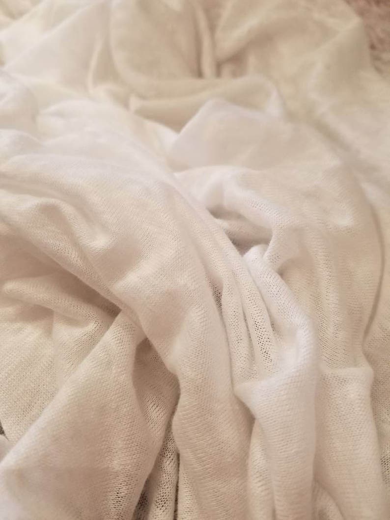 Puede incluir: Tela blanca con una superficie suave y texturizada. La tela est&aacute; arrugada y doblada, creando una sensaci&oacute;n de profundidad y dimensi&oacute;n.