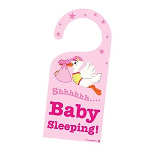 May include: Pink door hanger with a white stork carrying a pink baby bundle. The text on the hanger reads "Shhhhh... Baby Sleeping!"