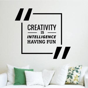May include: Black and white wall decal with the quote "Creativity is intelligence having fun" in a square frame with quotation marks.