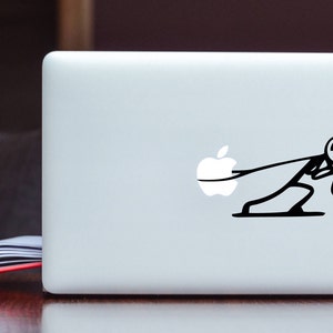 May include: A white laptop with a black sticker of a stick figure pulling a white Apple logo. The stick figure is sweating and looks stressed.