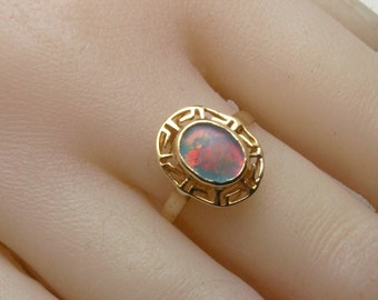 May include: A gold ring with an oval-shaped opal gemstone set in a geometric design.