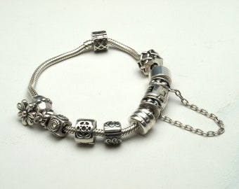 Heavy silver charm bracelet with nine charms and safety chain
