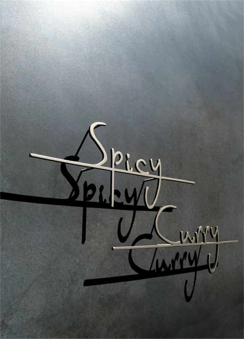 May include: A close-up of a dark grey wall featuring the words "Spicy Curry" in a metallic, cursive font. The words are connected by horizontal lines, creating shadows. The image evokes a restaurant or food-related setting.
