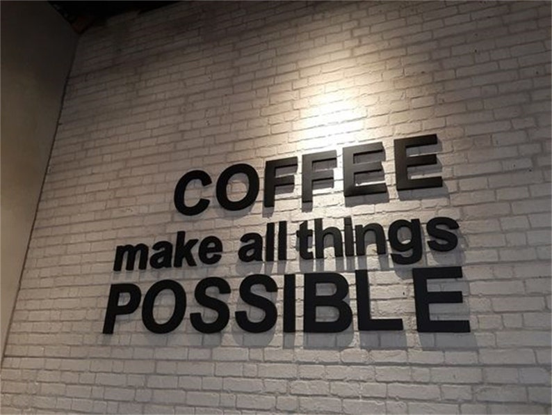 K&ouml;nnte beinhalten: Schwarz-wei&szlig;es Schild an einer wei&szlig;en Backsteinwand mit der Aufschrift "COFFEE make all things POSSIBLE".