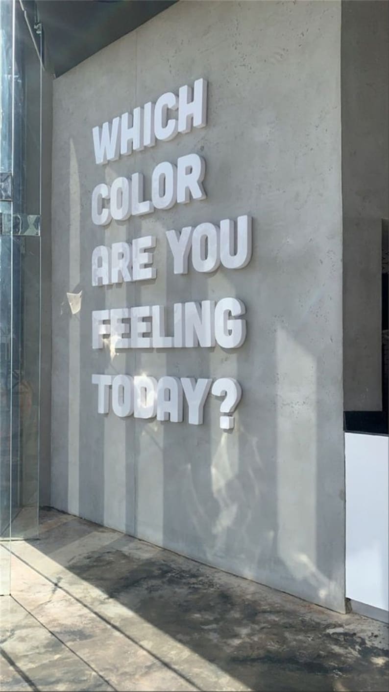 K&ouml;nnte beinhalten: Eine wei&szlig;e Wand mit dem Text "Welche Farbe f&uuml;hlst du dich heute?" in gro&szlig;en, wei&szlig;en 3D-Buchstaben.