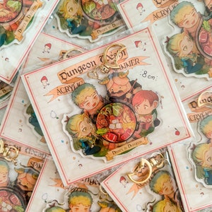 May include: A set of four acrylic keychains featuring characters from a fantasy game. The keychains are 8 cm in diameter and depict a group of adventurers enjoying a meal together. The keychains are packaged in a clear plastic bag with a white background and the text "Dungeon Design Acrylic Inner" printed on it.
