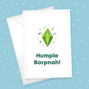 May include: A white greeting card featuring a green diamond-shaped plumbob illustration surrounded by small green confetti marks. Below the graphic, the text Humple Borpnah! is printed in a bold, dark green sans-serif font on the card surface.