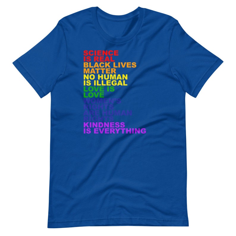 May include: A royal blue t-shirt with a rainbow-colored message that reads "Science is real, Black Lives Matter, No Human is Illegal, Love is Love, Kindness is Everything."