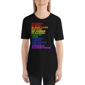 May include: Black t-shirt with a rainbow-colored message that reads "Science is real, Black Lives Matter, No Human is Illegal, Love is Love, Women's Rights are Human Rights, Kindness is Everything."