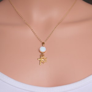 May include: A gold chain necklace with a white opal pendant and a charm featuring a Star of David and a cross.