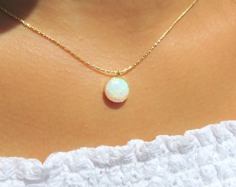 May include: A gold chain necklace with a white opal pendant. The opal is round and has a slight iridescent shimmer.