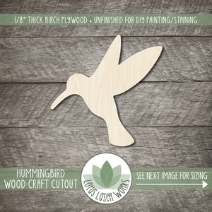 May include: Unfinished wooden hummingbird cutout, 1/8 inch thick birch plywood, for DIY painting or staining. The cutout is on a woodgrain background. The text "Hummingbird Wood Craft Cutout" is at the bottom of the image. The text "See next image for sizing" is at the bottom right of the image.