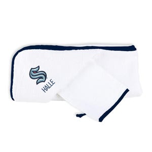 May include: White towel set with a navy blue trim. The set includes a larger rectangular towel and a smaller square towel. The logo of a stylized sea creature and the word "HALLE" are printed on the larger towel.