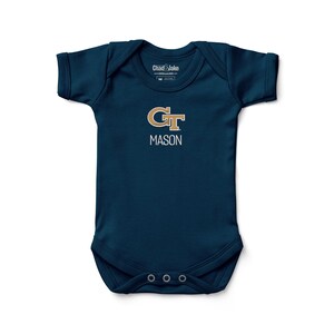 May include: Navy blue baby onesie with short sleeves. The onesie features the text "GT MASON" in gold and white. The onesie has three snaps at the bottom and a tag that says "Chad & Jake" at the top.