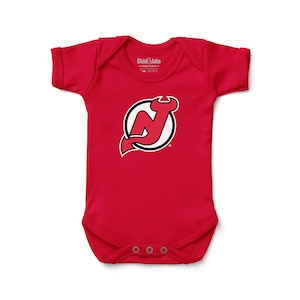May include: A red baby bodysuit featuring the New Jersey Devils logo. The logo is a stylized "N" with a devil's tail and horns, set within a white circle with a black outline. The bodysuit has short sleeves and snap closures.